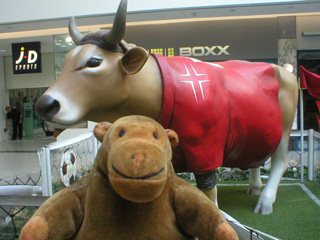 Mr Monkey beside a cow in a red number 7 football shirt