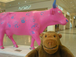 Mr Monkey in front of a pink cow covered in blue handprints