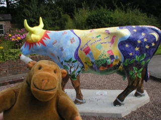 Mr Monkey in front of a cow with a trees for legs and the night sky on its rear 