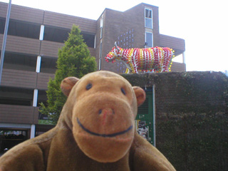 Mr Monkey looking up at a cow covered in liughtbulbs