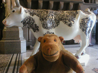Mr Monkey in front of a cow covered in Coronation Street characters