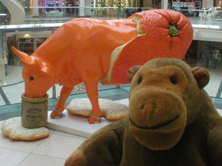 Mr Monkey in front of an orange cow, with its hindquarters covered in orange peel