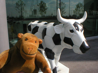 Mr Monkey in front of a cow decorated as a football