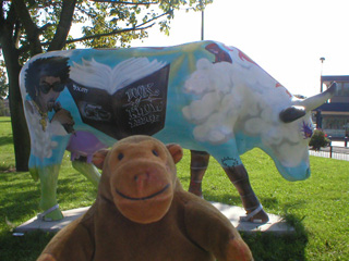 Mr Monkey in front of a cow with a singer, a book and some clouds on its side