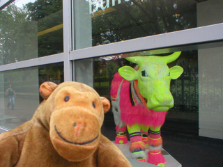Mr Monkey in front of a bright green cow