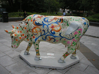 A cow covered in small ornate flowers and long blue swirls