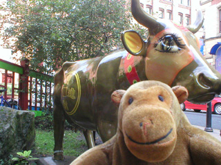 Mr Monkey in front of a cow decorated as a Chinese Lucky Cat