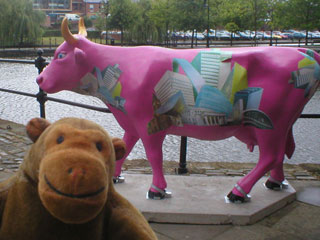 Mr Monkey with a pink cow covered in pictures of Mancunian buildings