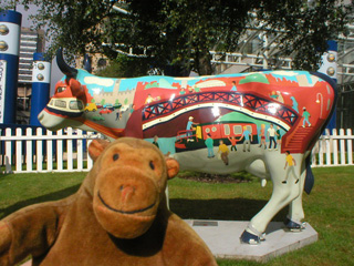 Mr Monkey in front of a cow with a bridge painted on its side