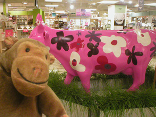 Mr Monkey beside a pink cow covered in large white, red, and purple flowers
