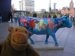 Mr Monkey in front of a blue cow covered in sea creatures