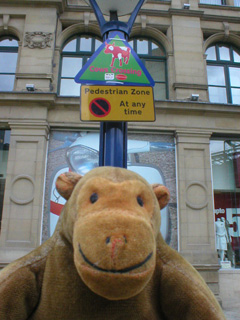 Mr Monkey standing in front of a 'Cows Crossing' sign