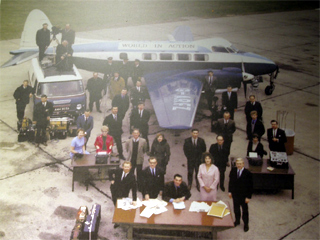 The World in Action team with their plane, van and desks on a runway