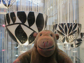 Mr Monkey looking at glass bowls by Gillies Jones