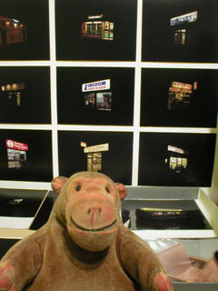 Mr Monkey in front of a group of photos by Jamie Lau