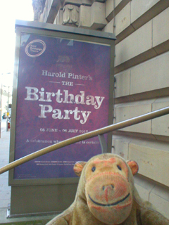 Mr Monkey looking at the The Birthday Party poster outside the theatre