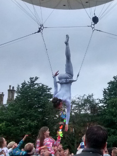 The moon acrobat reaching down to children in the crowd