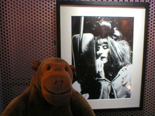 Mr Monkey looking at a picture of a man checking his make-up in a coach wing mirror