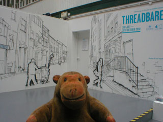 Mr Monkey looking at two large street scenes by Debbie Smyth