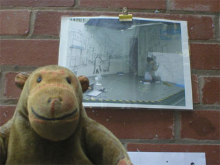 Mr Monkey looking at a photo of Debbie Smyth installing her street scenes