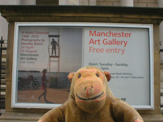 Mr Monkey examining the poster advertising the exhibition on the railings outside the gallery