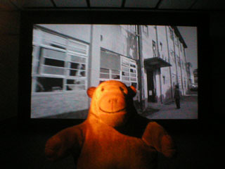 Mr Monkey watching the film : a man standing outside the Western Enterprises building