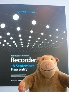 Mr Monkey looking at the poster outside the exhibition