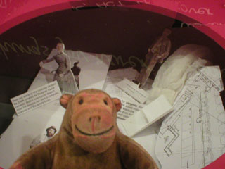 Mr Monkey looking at costume designs displayed in the Education Lounge coffee table