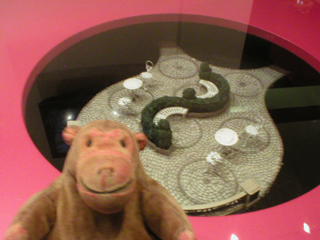 Mr Monkey looking at a set design displayed in the Education Lounge coffee table