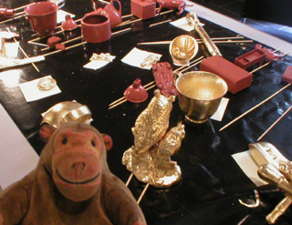 Mr Monkey looking at items covered with glue, ready for gilding
