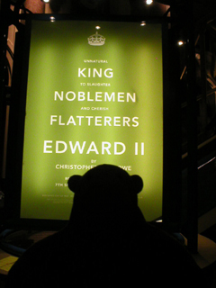 Mr Monkey looking at the King Noblemen Flatterers poster inside the theatre