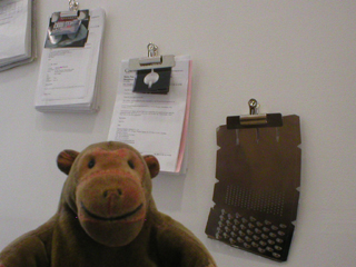 Mr Monkey looking at email printouts and a defective cheese grater