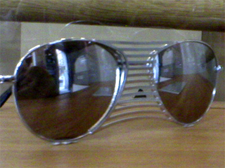 A pair of unwearable sunglasses, with a reflection of Mr Monkey