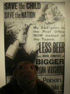 Mr Monkey looking at a poster exhorting workers to go to the Post Office instead of the pub