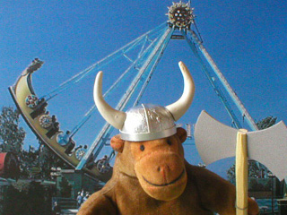 Monkey in a horned helmet in front of a swinging longship ride