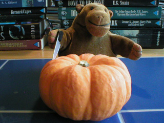 Mr Monkey wielding a knife over the top of a small pumpkin