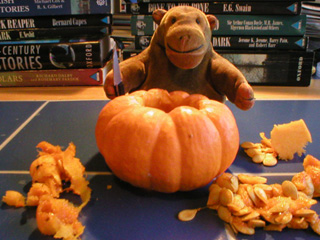 Mr Monkey with a hollowed out pumpkin and piles of pumpkin flesh and seeds