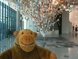 Mr Monkey in front of a large installation representing the dust cloud from the bomb going off