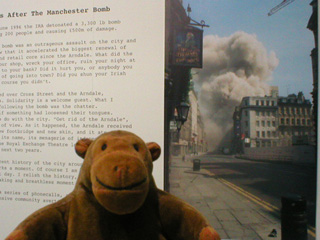 Mr Monkey in front of a large photo of the bomb going off