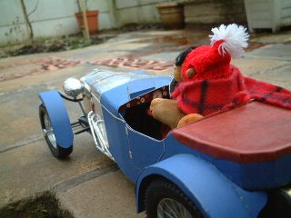 Mr Monkey driving away in woolly hat and scarf
