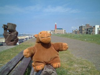 Mr Monkey on a bench, with a statue behind him