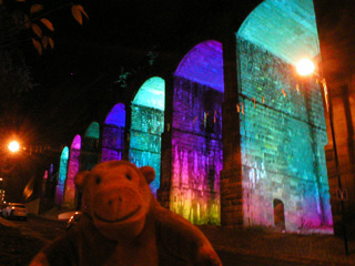 Mr Monkey looking at illuminated railway arches