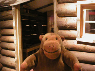 Mr Monkey looking at a replica log cabin