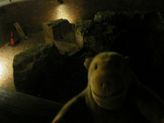 Mr Monkey looking at some bits of medieval wall in a pit