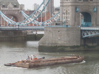 A tug guiding a barge under Tower Bridge
