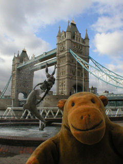 Mr Monkey looking at the girl and dolphin sculpture and Tower Bridge