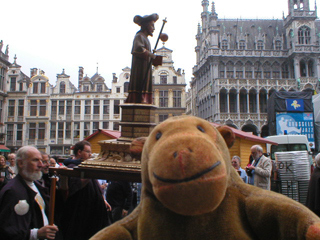 Mr Monkey watching a statue of St James being carried through the Grand Place
