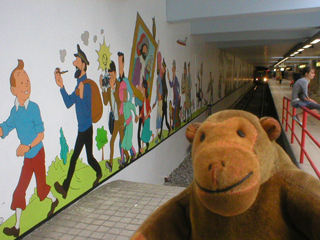 Mr Monkey looking at a mural along the tunnel wall at Stokkel metro station