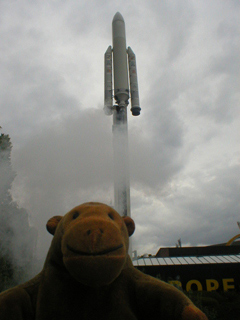 Mr Monkey looking at the Ariane rocket stopped at the top of a pole