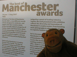 Mr Monkey looking at the Best of Manchester exhibition sign